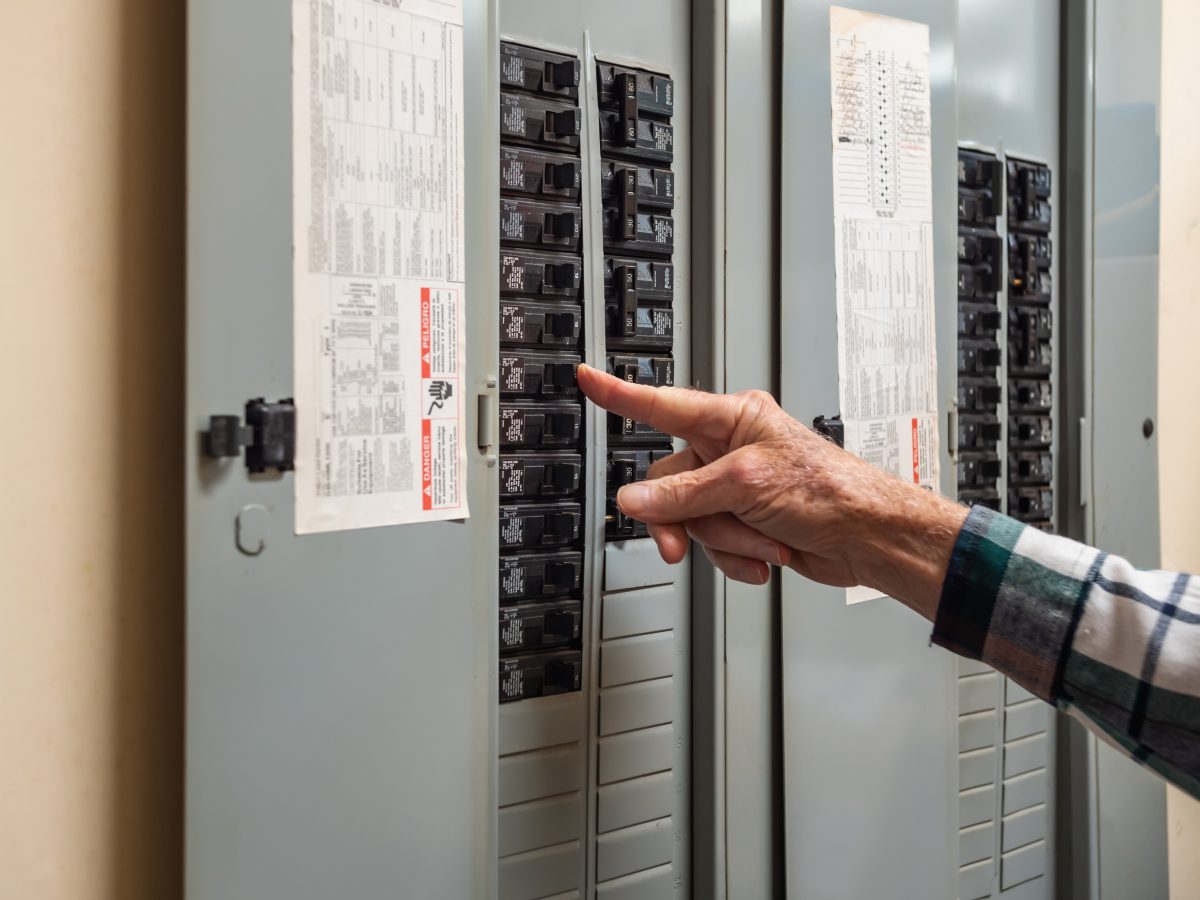 An image of a person flipping a switch on a circuit breaker.