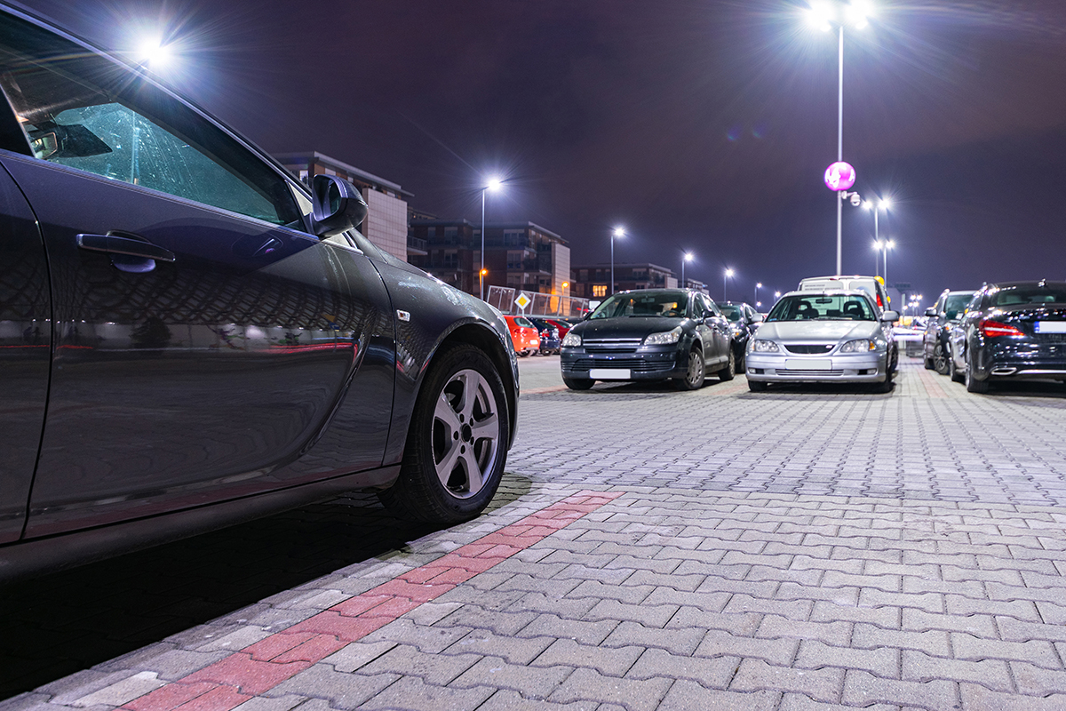 Cars in a lit up parking lot outside a commercial building.