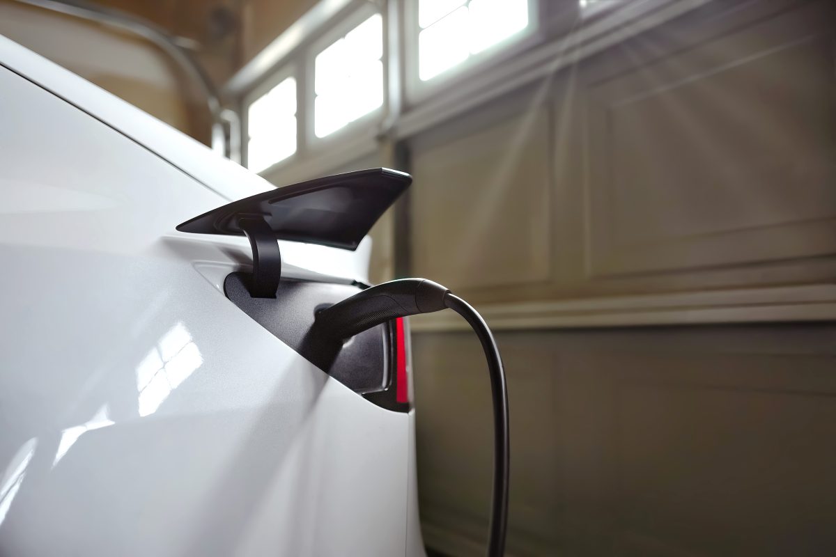 A white car inside a garage is being charged with an EV charger.