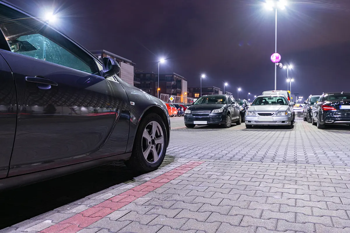 Well-lit parking lot with multiple vehicles at night under bright LED lighting