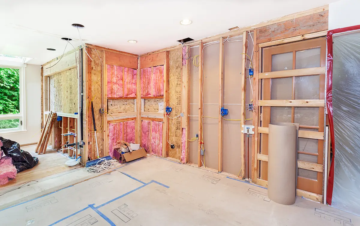 Home addition under construction with exposed wooden framing and pink insulation