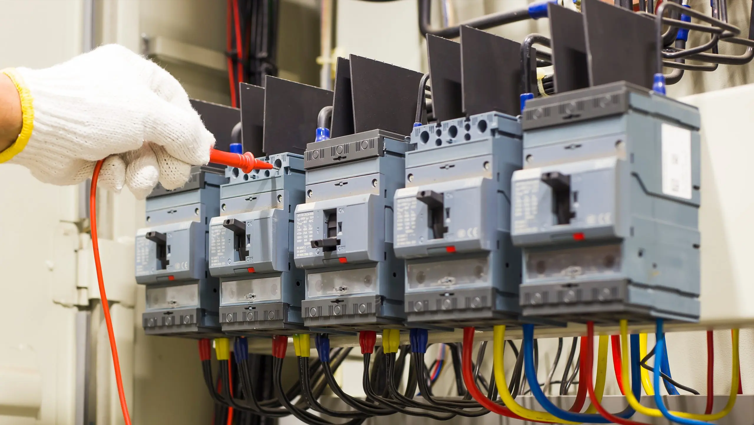 Electrician installing multiple gray circuit breakers in electrical panel