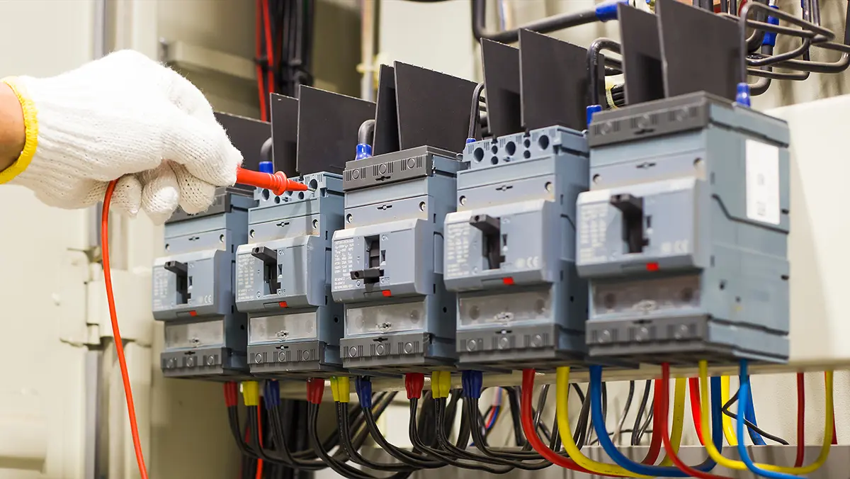 Electrician's gloved hand adjusting commercial electrical circuit breakers and switches
