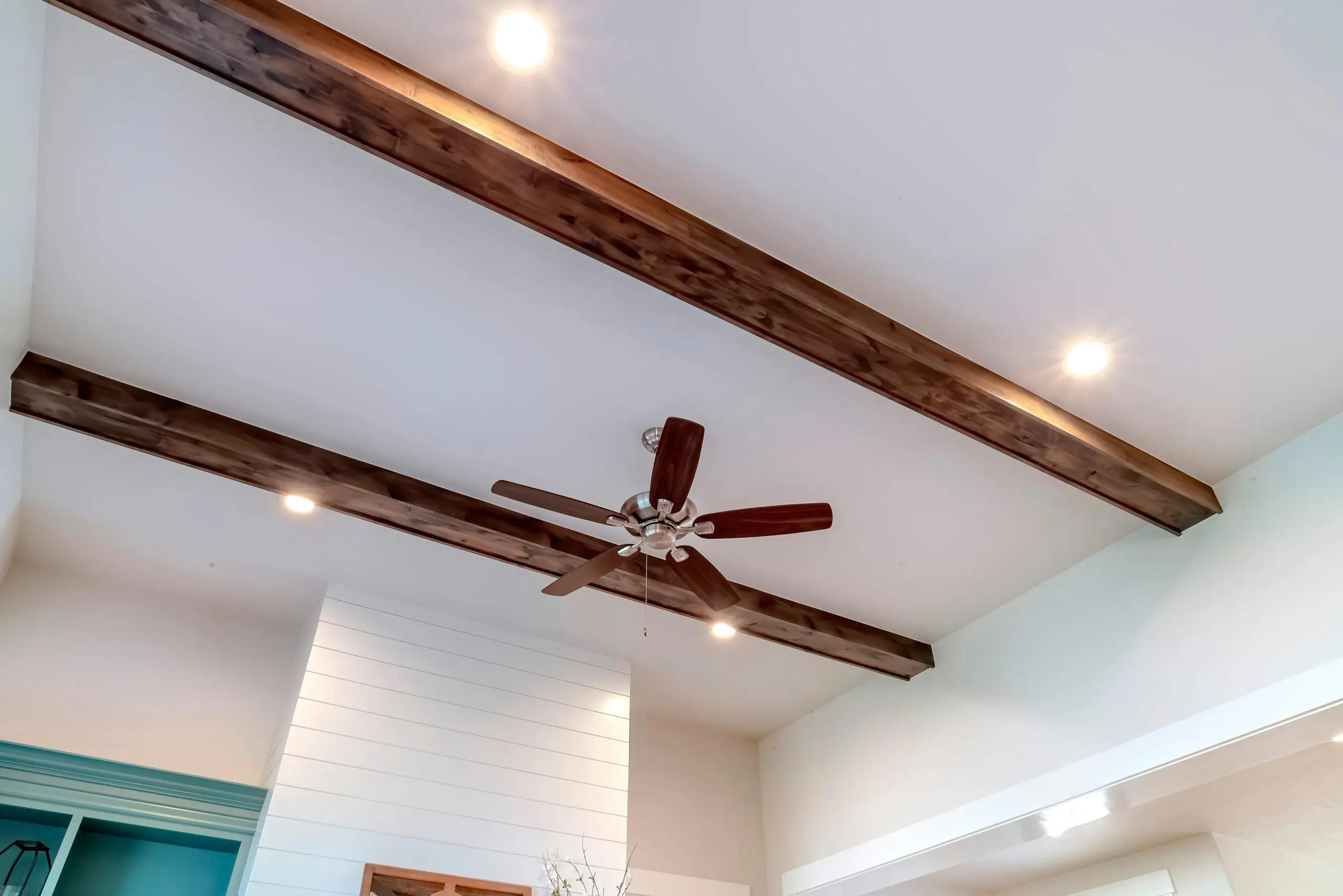 Recessed ceiling lights and dark wood beams in modern white interior